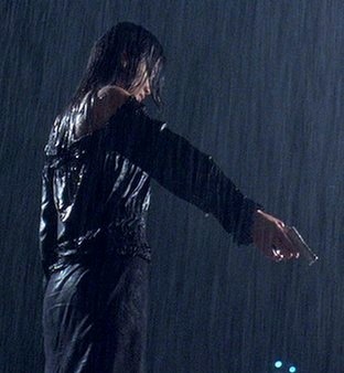 Lynn stands in the rain holding a gun
